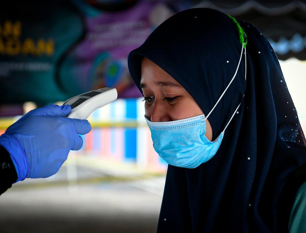 A voter has her body temperature taken before being allowed to enter the polling place for the Chini by-election at the KAFA Felda Chini 3 day. - Bernama
