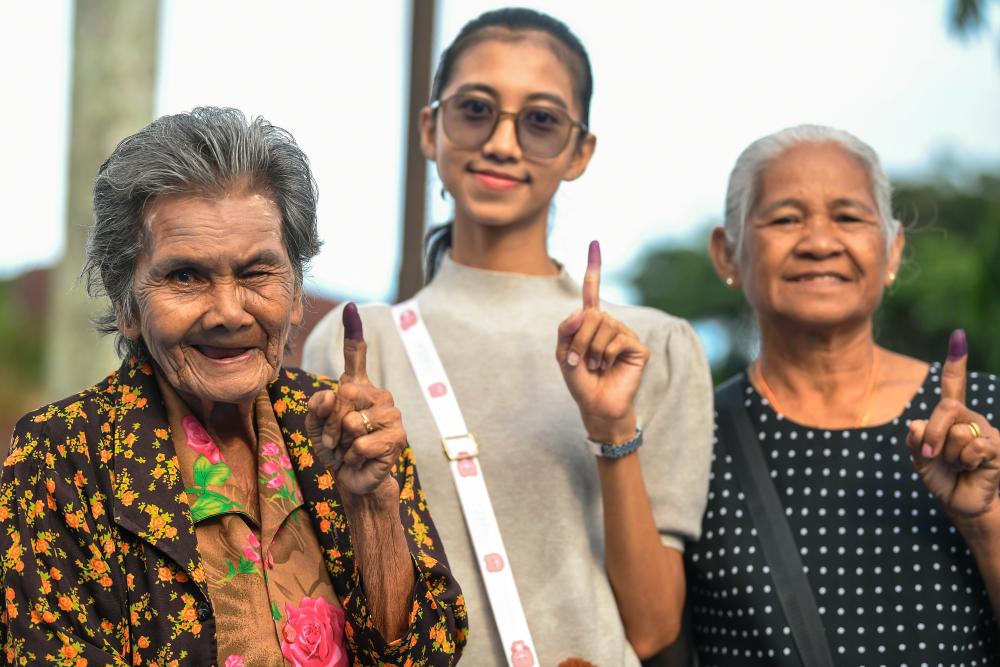 Pengundi Masyarakat Siam, Kuat Din Shai,79 (kiri) bersama jirannya I From Eput, 67 (kanan) dan Wandy Ai Yem, 28, (tengah) tersenyum sambil menunjukkan jari yang dicelup dakwat selepas menunaikan tanggunjawab mereka mengundi bagi Dewan Undangan Negeri (DUN) Pedu pada Pilihan Raya Negeri di Pusat Pengundian Sekolah Kebangsaan Naka di sini hari ini/BERNAMAPix