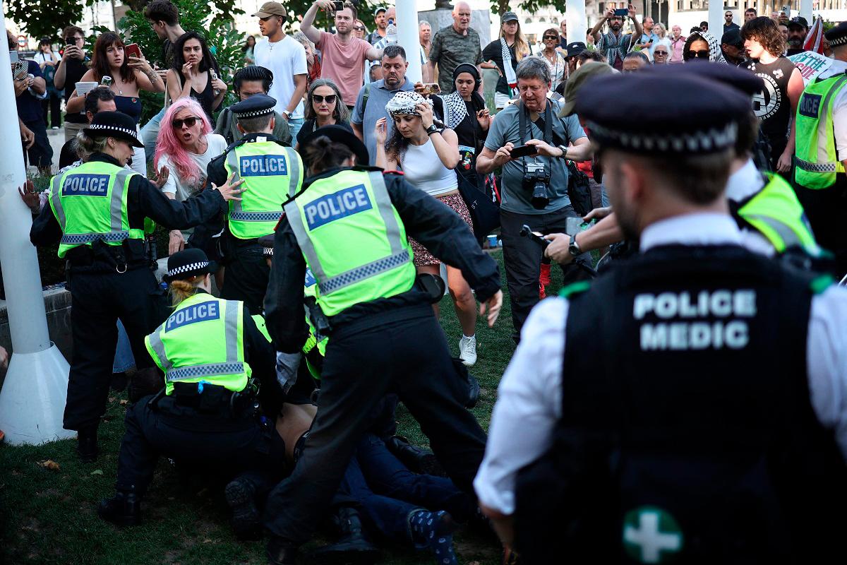 A protester is arrested by police officers at a Lift The Ban demonstration in support of the proscribed group Palestine Action, calling for the recently imposed ban to be lifted, in Parliament Square, central London, on August 9, 2025. Organisers expect at least 500 people to turn up to a new demonstration in support of Palestine Action today, and police have warned all demonstrators could face arrest. Palestine Action was proscribed under the 2000 Terrorism Act. - HENRY NICHOLLS / AFP