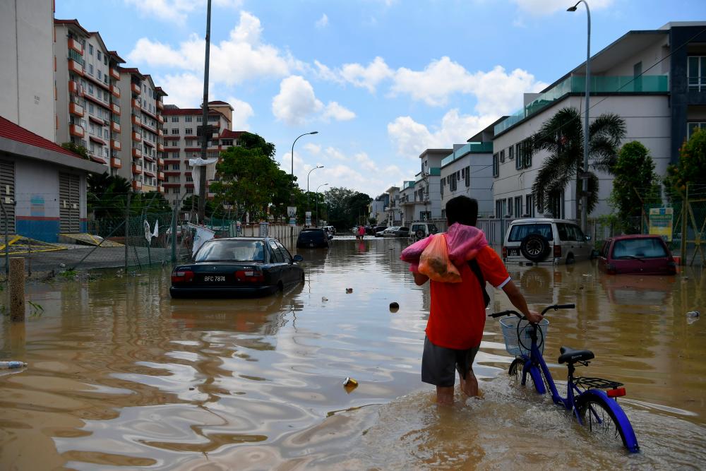 A resident of Taman Kristal, Dengkil leaves ​​his house into the flooded area today. - Bernama
