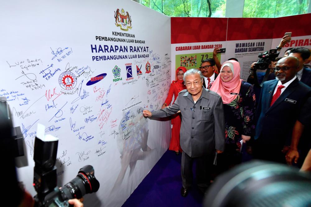 Prime Minister Tun Dr Mahathir Mohamad shows off the ‘Harapan Rakyat’ space that he signed, along with members of the public during the launch of the Rural Development policy at the Putrajaya International Convention Center (PICC) today. - Bernama