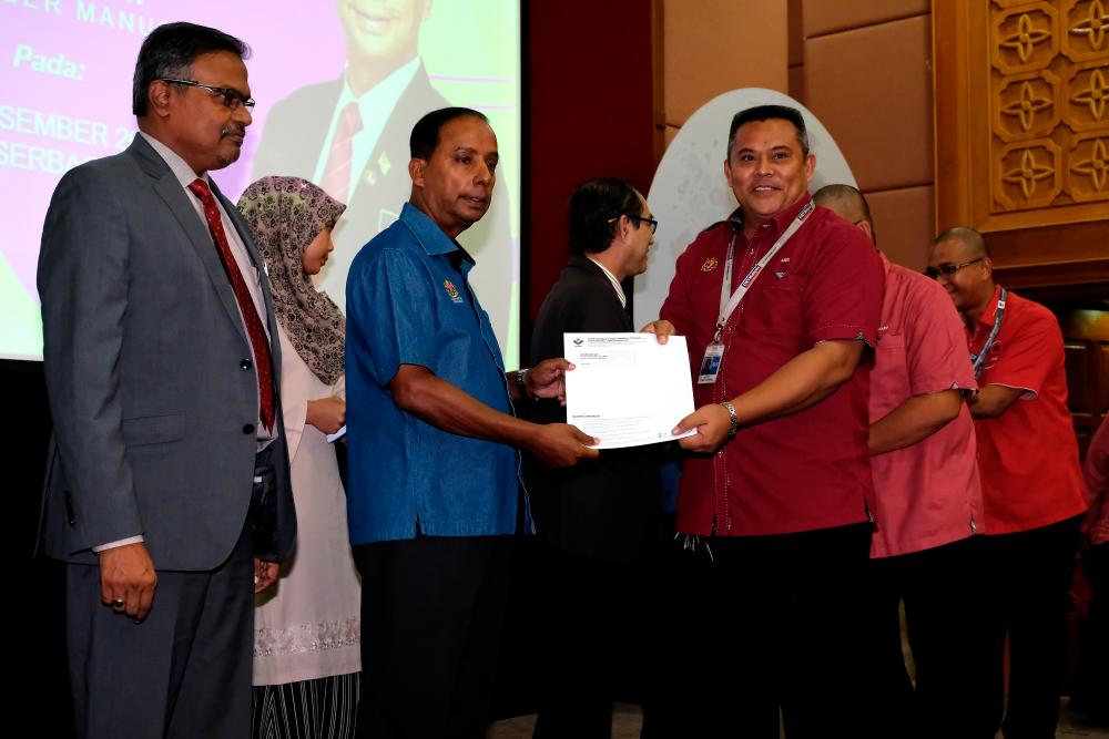 Human Resources Minister M. Kula Segaran hands over special financial assistance to 190 staff who are from bottom 40% household income group in Putrajaya today. - Bernama
