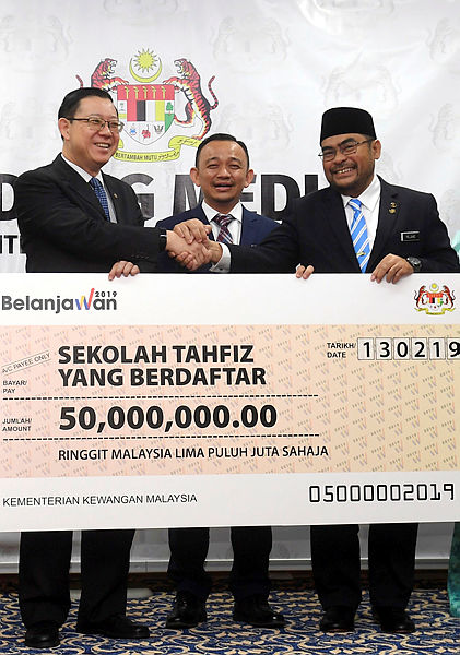 Finance Minister Lim Guan Eng (L) hands over a RM50 million cheque to rMinister in the Prime Minister’s Department Datuk Seri Mujahid Yusof Rawa for the maintenance and upgrading of registered tahfiz schools nationwide, at the Finance Ministry on Feb 13, 2019. — Bernama