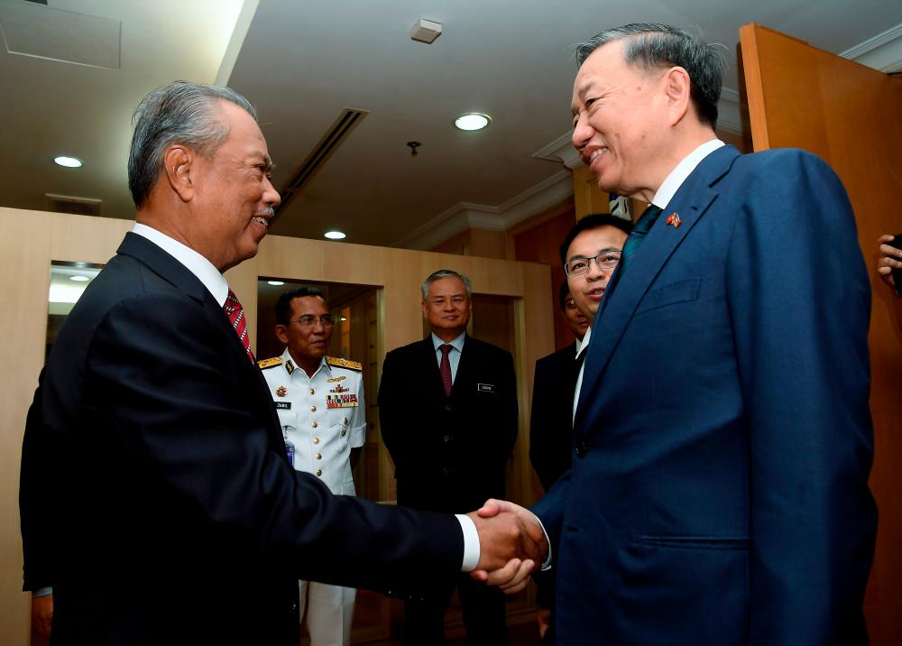 Home Minister Tan Sri Muhyiddin Yassin (left) shake hands with Vietnamese Public Security Minister General To Lam during a courtesy call by the latter here today. - Bernama