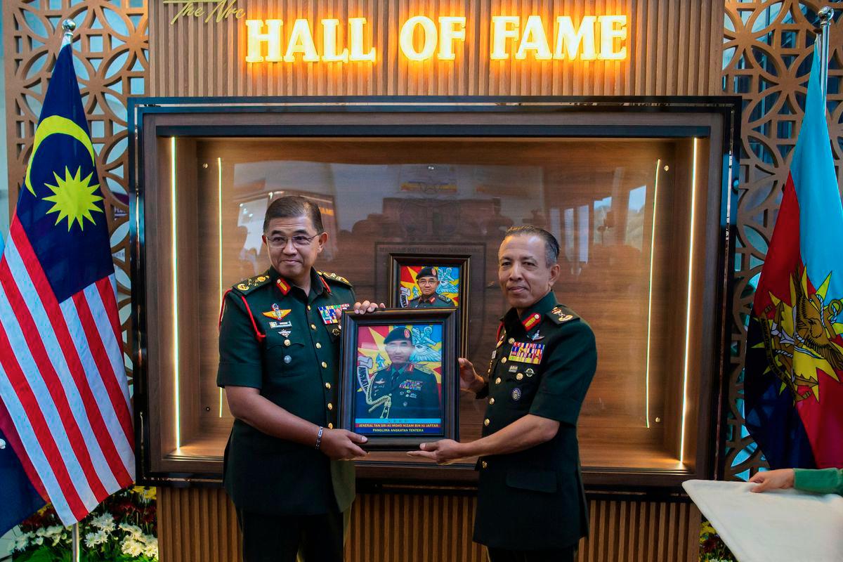 Malaysian Armed Forces (MAF) Chief General Tan Sri Mohd Nizam Jaffar (left) receives a souvenir from National Resilience College Commandant Brigadier General Abdul Karim Ahmad as they pose for a photo at the inaugural National Resilience College (MKN) Hall of Fame Proclamation Ceremony at MKN today. – BERNAMA