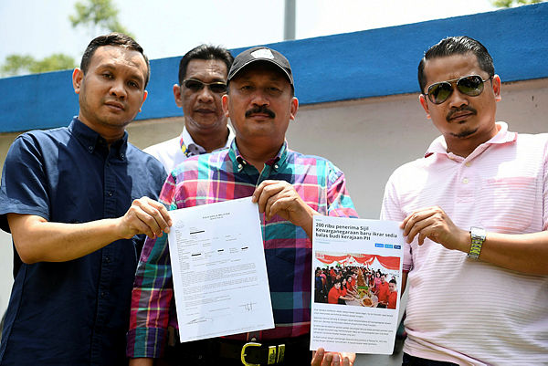 NRD Director Datuk Ruslin Jusoh showing the police report made today on the social media user who made posts titled “200,000 new recipients of citizenship vow to repay the government”, at the Putrajaya District Police Headquarters. — Bernama