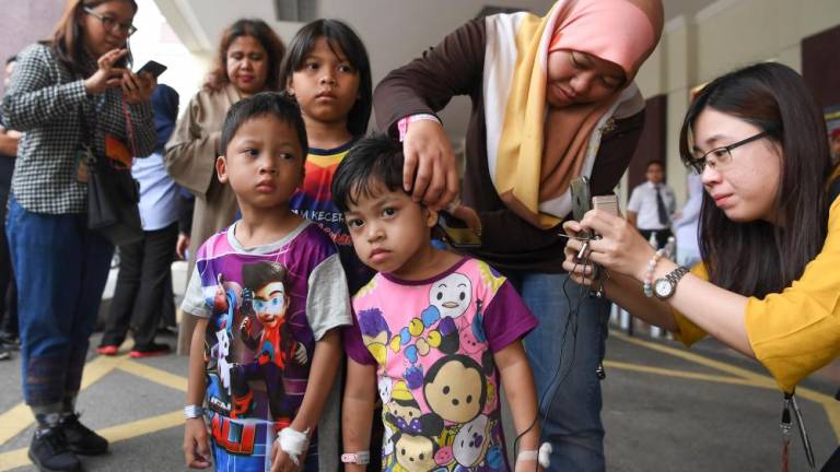 Sri Rahayu Sugiono (2nd R) shows the scalding suffered by her son Mohd Haffizal Khalid, 5, following a helium balloon explosion, on Oct 12, 2019. — Bernama