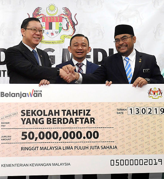 Finance Minister Lim Guan Eng (L) hands over a RM50 million cheque to Minister in the Prime Minister’s Department Datuk Seri Mujahid Yusof Rawa for the maintenance and upgrading of registered tahfiz schools nationwide, at the Finance Ministry on Feb 13, 2019. — Bernama