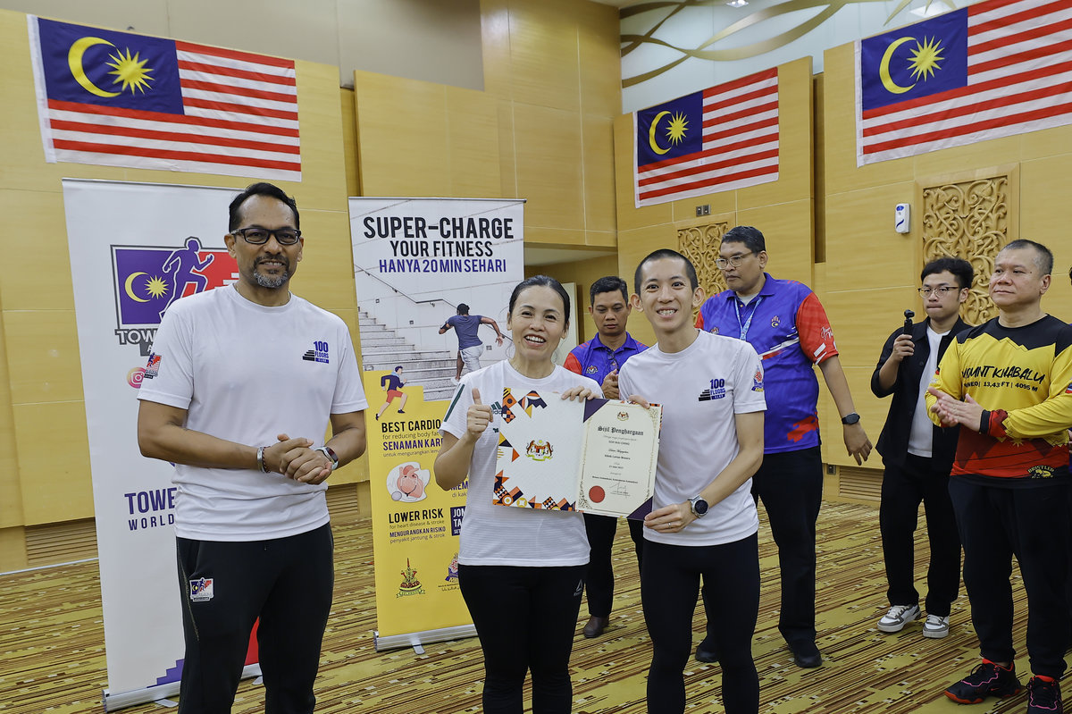 Deputy Minister of Communications Teo Nie Ching presents a certificate of appreciation to national tower running champion Soh Wai Ching after he climbed to the 37th floor of the Communications Tower during the Stair Climbing Clinic programme today. – BERNAMA
