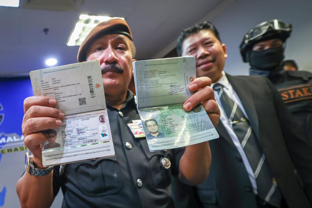 Ketua Pengarah Imigresen Datuk Ruslin Jusoh menunjukkan perbandingan pasport asli dengan pasport palsu (kanan) semasa sidang media hari ini/BERNAMAPix