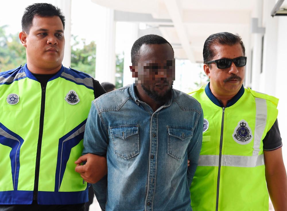 The Nigerian suspect, Alowonle Oluwajuwon Gilbert, being escorted by police personnel. Picture from May 23, 2019. - Bernama