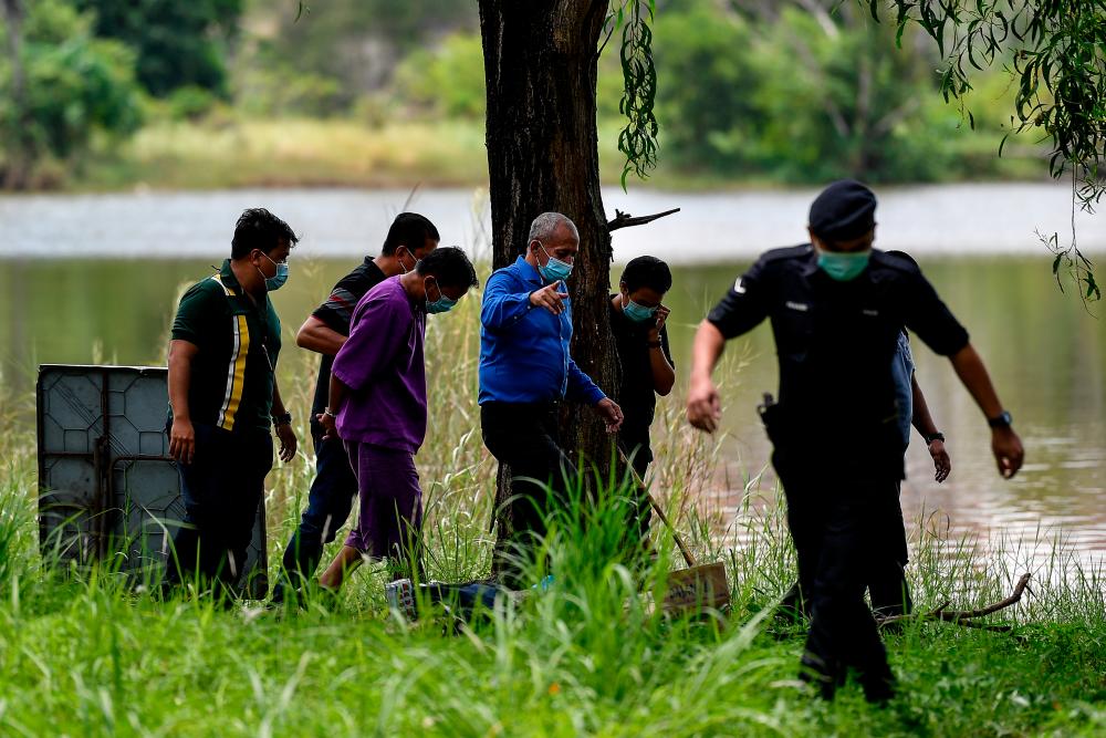 The suspect is brought to the location of the murder – at Tasik Taman Putra Perdana Putrajaya – to assist investigators who were combing the area for evidence, on Aug 4, 2020. — Bernama