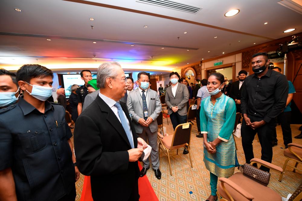 Prime Minister Tan Sri Muhyiddin Yassin is greeted by YouTuber Sugu Pavithra and her husband M. Sugu, after the launch of the 50th anniversary of Rukun Negara in Putrajaya, on July 9, 2020. — Bernama