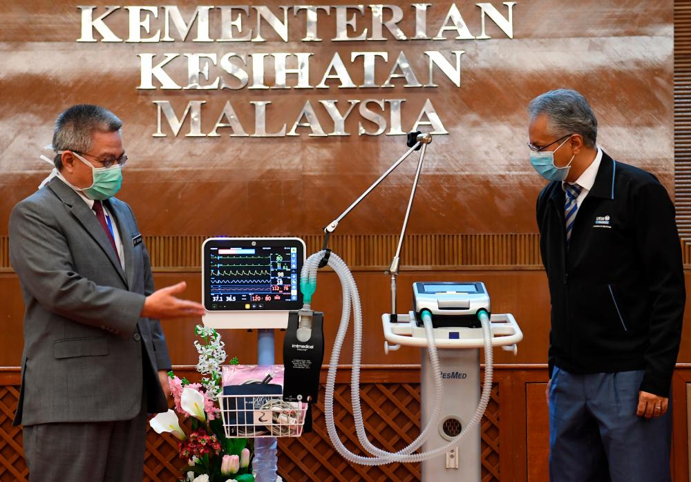 UEM Edgenta managing CEO Datuk Azmir Merican (R) poses for a photo with Health Minister Datuk Seri Dr Adham Baba and a ventilator, at the latter’s officer, on April 1, 2020.