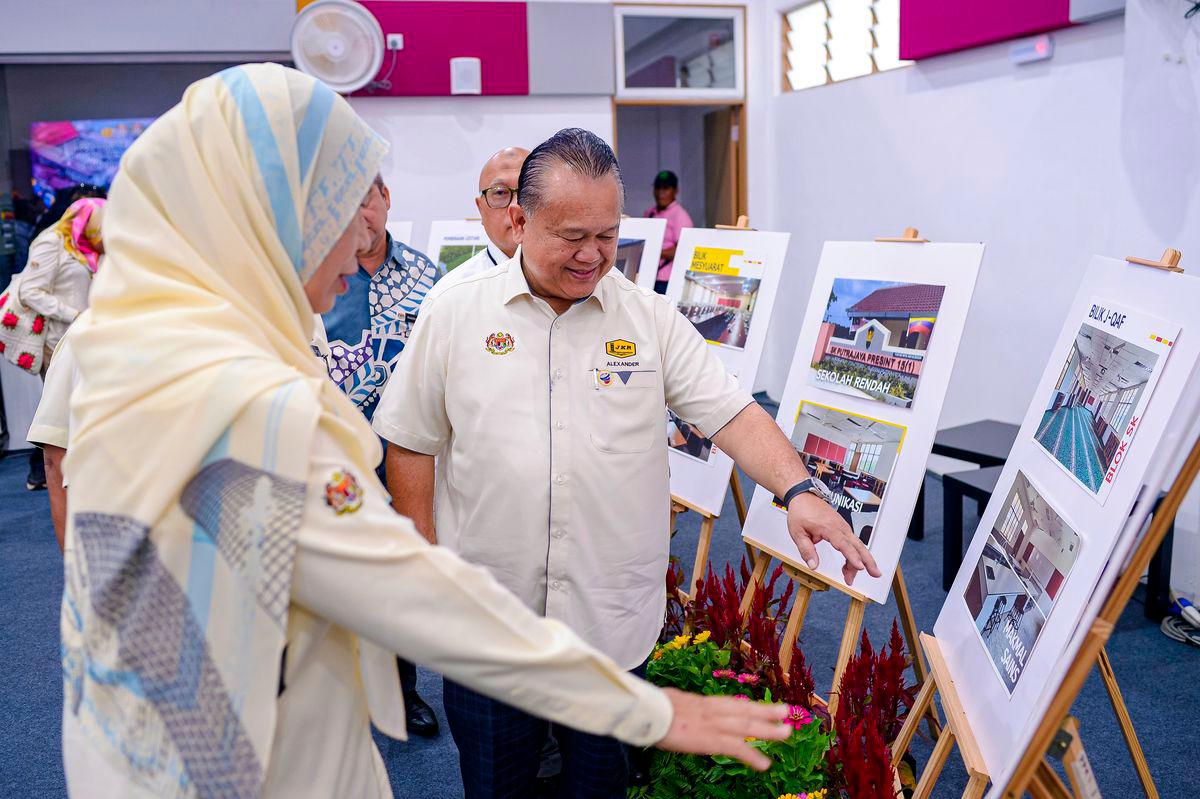 Works Minister Datuk Seri Alexander Nanta Linggi views images of the school construction project during the Handover Ceremony of the New School Construction Project at the Precinct 15 School Complex today. - BERNAMAPIX