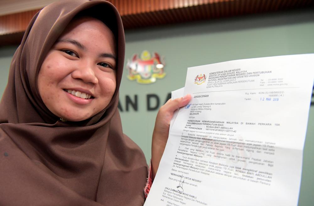 Roisah Abdullah holds up her certificate of approval for citizebship at the Home Ministry in Putrajaya on March 28, 2019. — Bernama