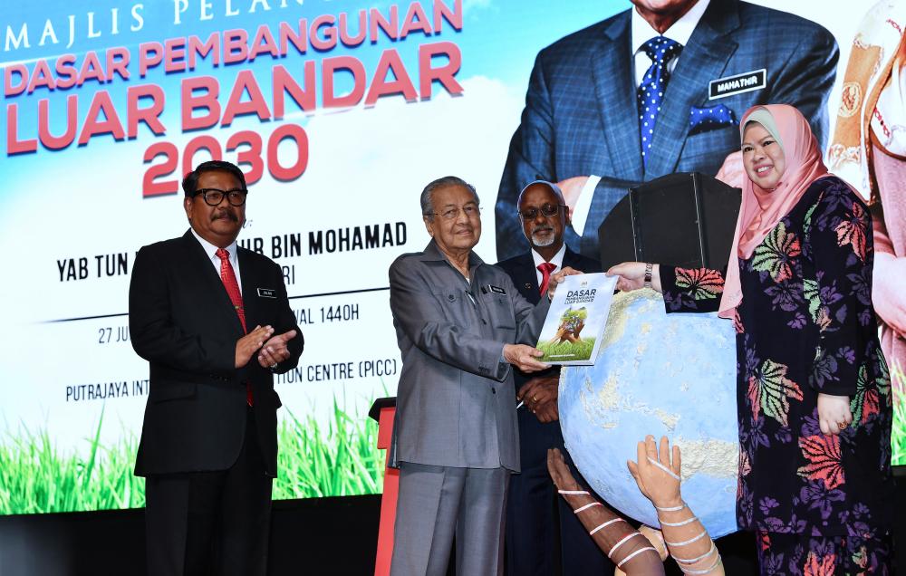 Prime Minister Tun Dr Mahathir Mohamad (2nd from L) receives the Rural Development Policy Book 2030 from Rural Development Minister Datuk Seri Rina Mohd Harun (R) after launching the policy at the Putrajaya International Convention Center (PICC) today. - Bernama