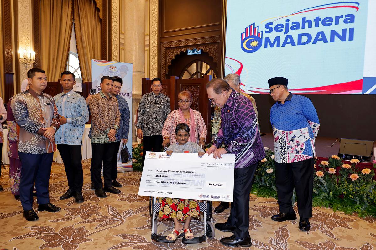Prime Minister Datuk Seri Anwar Ibrahim presents a contribution to one of the recipients, Mageswary Muruthamuthu, at the Launch Ceremony of the Malaysia MADANI People’s Wellbeing Initiative (Sejahtera MADANI) at the Seri Perdana Complex here today. - BERNAMAPIX