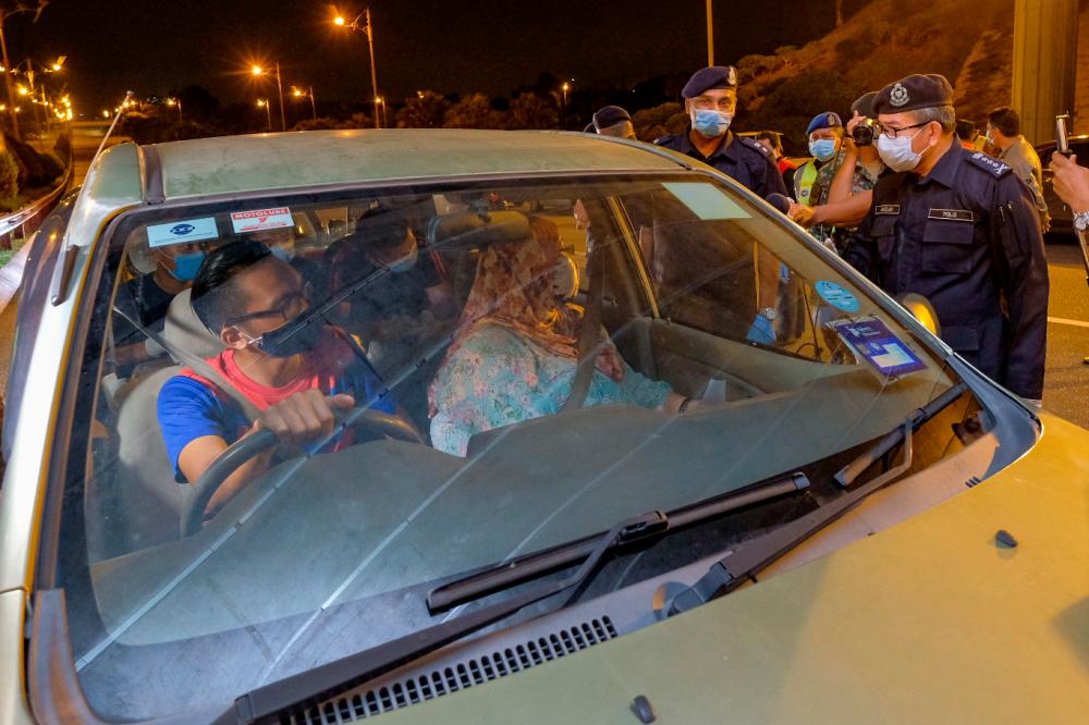 Kuala Lumpur police chief Datuk Seri Mazlan Lazim speaks to a motorist who was out with his family, at a roadblock in Serdang, on March 28, 2020. — Bernama