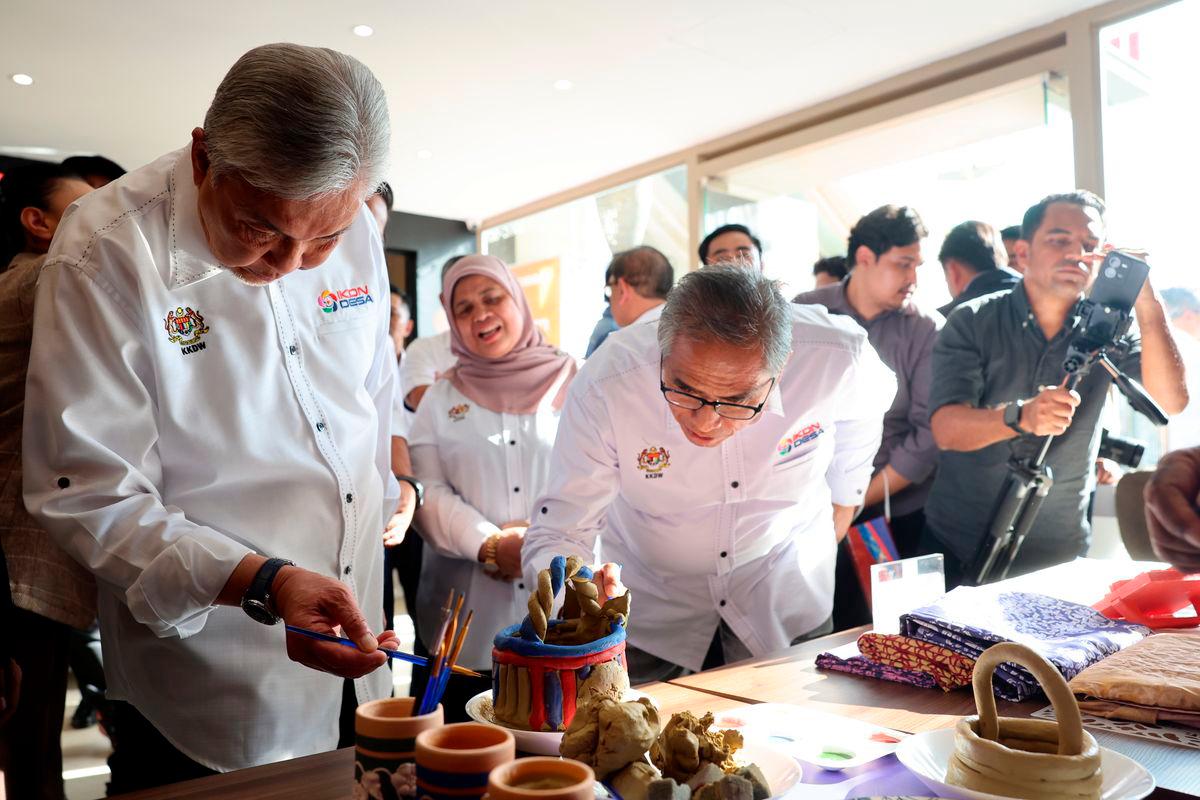 Timbalan Perdana Menteri merangkap Menteri Kemajuan Desa dan Wilayah (KKDW), Datuk Seri Dr Ahmad Zahid Hamidi (kiri) mewarnakan labu sayong pada Majlis Pelancaran IkonDesa@Putrajaya di Souq Putrajaya, Presint 1, hari ini. Turut kelihatan Ketua Setiausaha Negara, Tan Sri Shamsul Azri Abu Bakar (tiga kiri) dan Timbalan Menteri (KKDW), Datuk Rubiah Wang (tengah)- BERNAMA