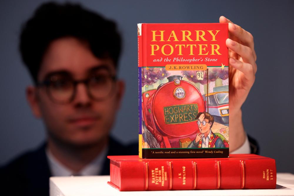 Rare Books Specialist and curator Mark Wiltshire poses with a rare first edition copy of 'Harry Potter and the Philosophers Stone'. - REUTERSPIX