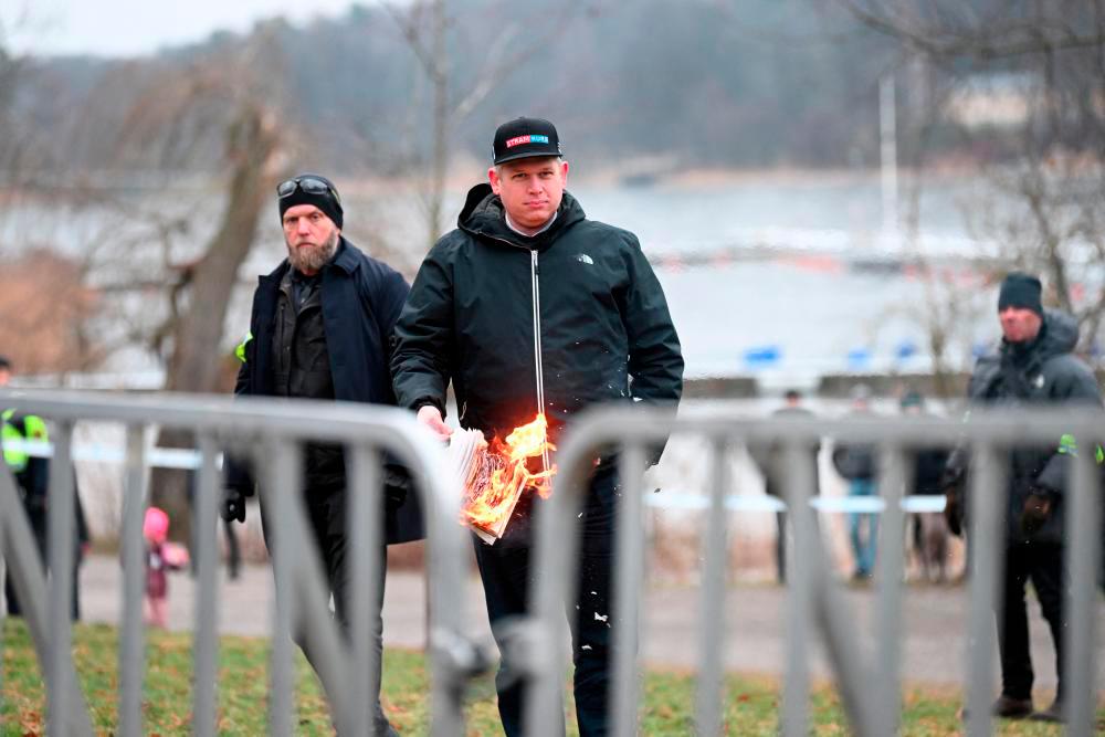 Leader of the far-right Danish political party Stram Kurs Rasmus Paludan burns a copy of the Qoran during a manifestation outside the Turkish embassy in Stockholm, Sweden, January 21, 2023. - REUTERSPIX