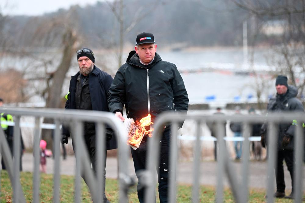 Leader of the far-right Danish political party Stram Kurs Rasmus Paludan burns a copy of the Koran during a manifestation outside the Turkish embassy in Stockholm, Sweden, January 21, 2023. - REUTERSPIX