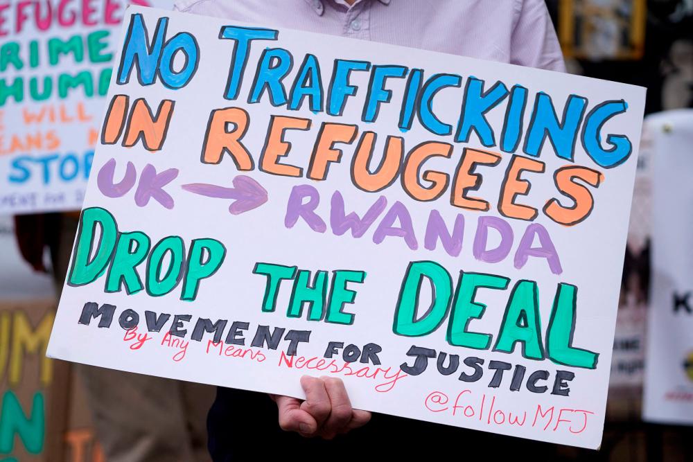 Demonstrators hold placards as they protest against Britain's plan to deport asylum seekers to Rwanda, outside the High Court in London. - AFPPIX