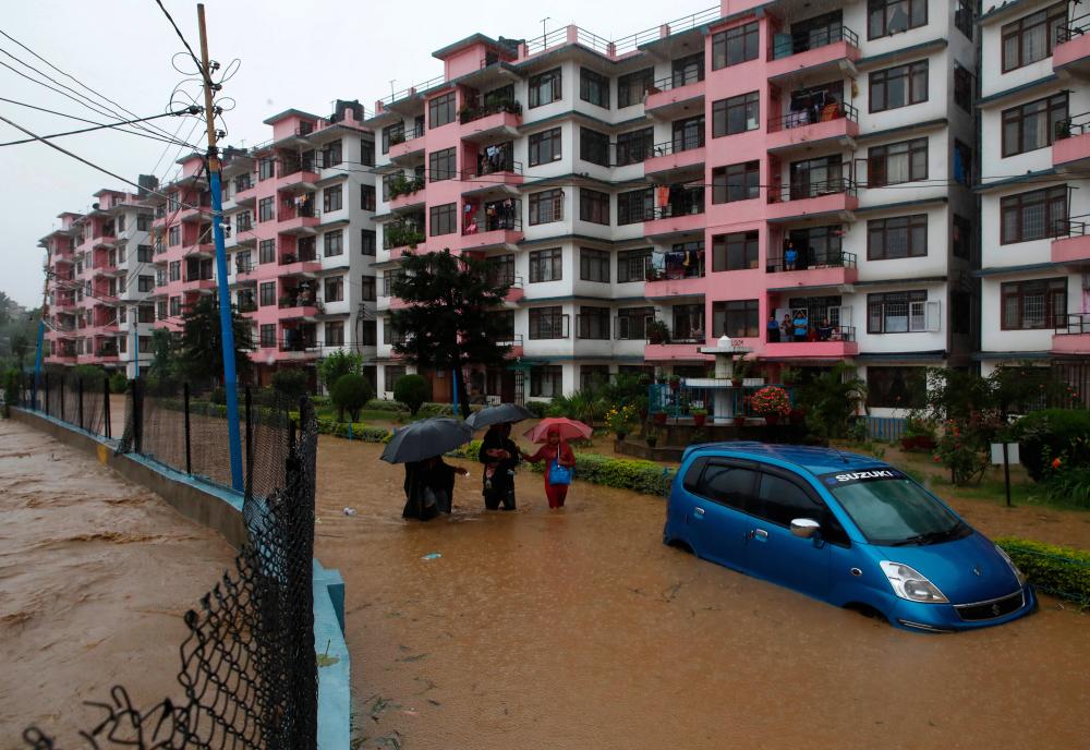 Residents walk towards dry ground from a flooded colony in Kathmandu, Nepal July 12, 2019. - Reuters