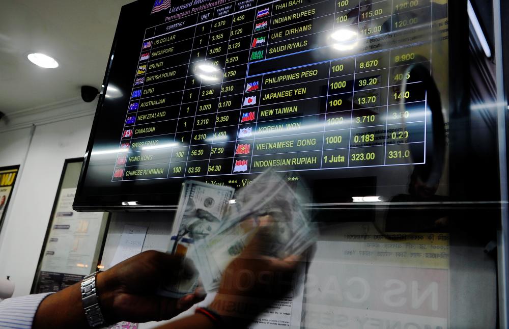 An employee counts US dollar banknotes at a currency exchange outlet in Kuala Lumpur. Kenanga Research maintains its ringgit-to-US dollar end-of-year forecast at RM4.15. – Bernama