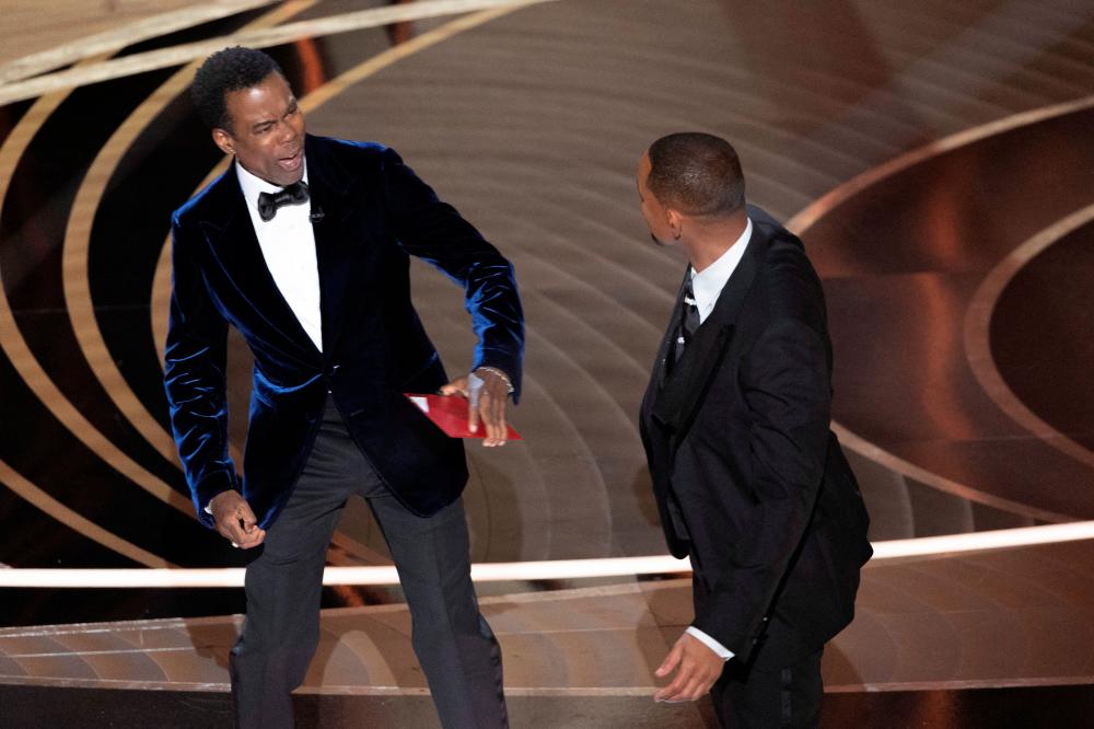 Chris Rock reacts after being hit by Will Smith (R) as Rock spoke on stage during the 94th Academy Awards in Hollywood, Los Angeles, California, U.S., March 27, 2022. REUTERSpix