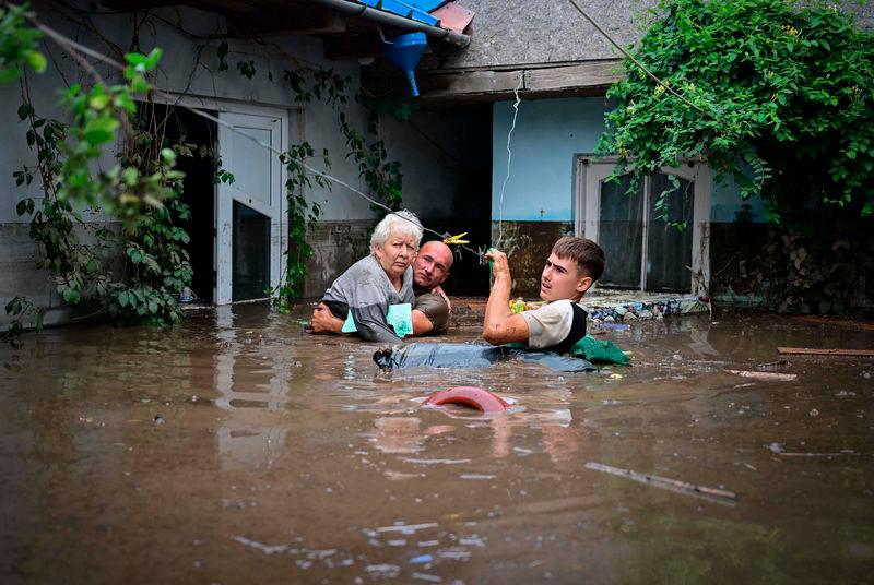 Local residents rescue an elderly man (C) from the rising flood waters in the Romanian village of Slobozia Conachi - AFPpix