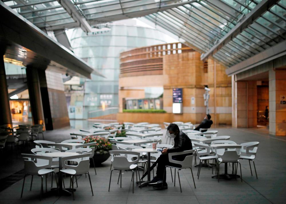 People wearing protective face masks take a rest next to almost empty seats of a cafe and restaurant at the Roppongi Hills complex in Tokyo today. – REUTERSPIX