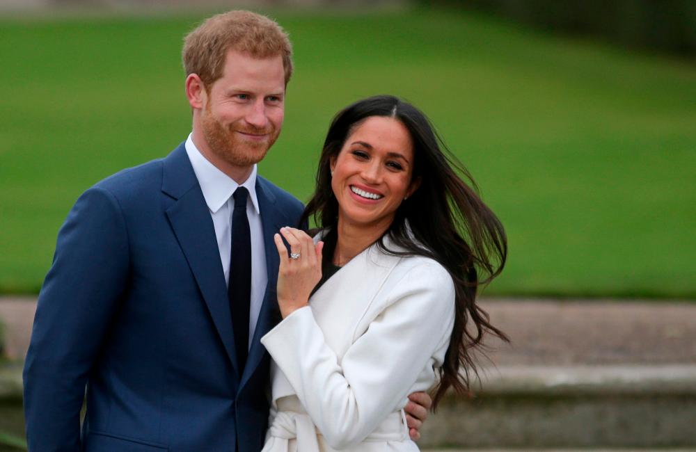 In this file photo taken on on Nov 27, 2017, Britain's Prince Harry stands with his fiancee US actress Meghan Markle as she shows off her engagement ring whilst they pose for a photograph in the Sunken Garden at Kensington Palace in west London, following the announcement of their engagement. — AFP