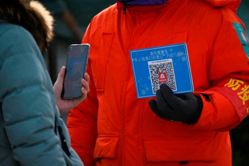 A woman using her mobile phone to scan a QR code for health registration before entering an outdoor ice rink in Beijing. — AFP