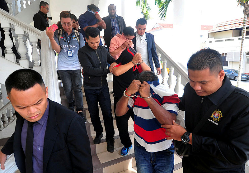 The officers are led out of the George Town court complex, on April 21, 2019. — Bernama