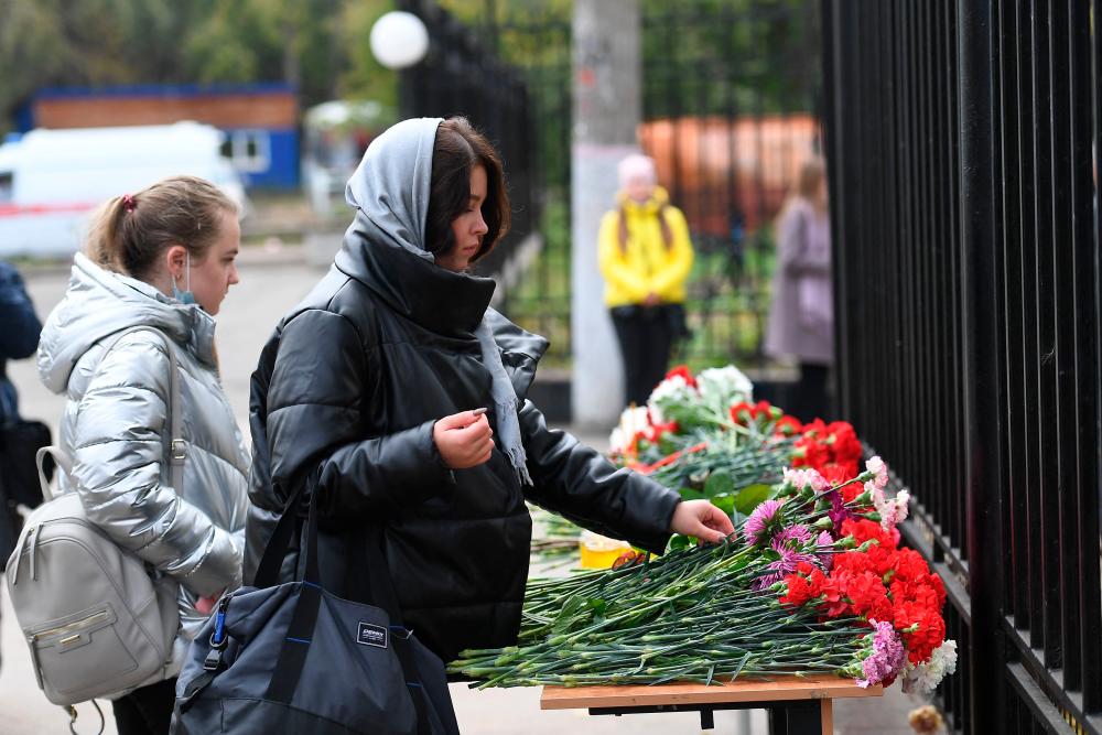 Women lay flowers at the entrance of the university campus in Perm on September 21, 2021 one day after a gunman killed six people on a university campus in Russia before being detained. AFPpix