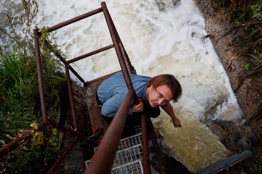 Environmental activist Egor Chastukhin takes water from the sewerage of a paper factory on the bank of Sura river in Penza, on August 22, 2023. AFPPIX