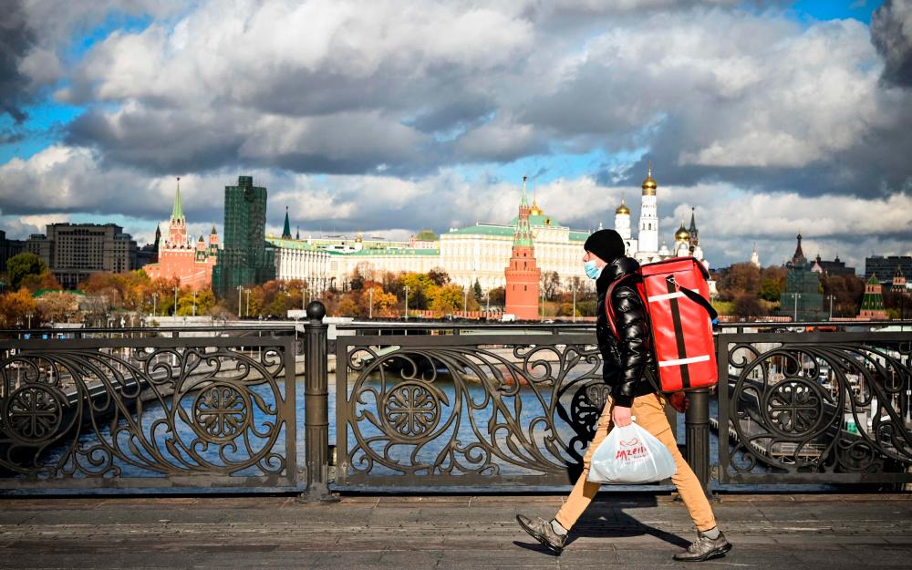 A food delivery courier wearing a protective mask walks in front of the Kremlin in central Moscow, on October 18, 2021, amid the outbreak of Covid-19, caused by the novel coronavirus. AFPpix