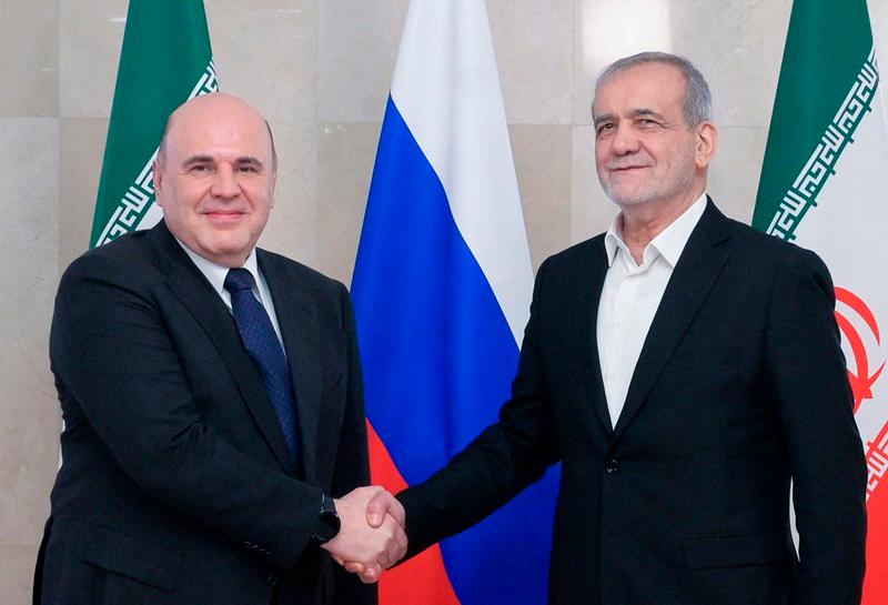 In this pool photograph distributed by the Russian state agency Sputnik, Russia's Prime Minister Mikhail Mishustin meets with Iran's President Masoud Pezeshkian in Moscow on January 17, 2025. (Photo by Alexander ASTAFYEV / POOL / AFP)