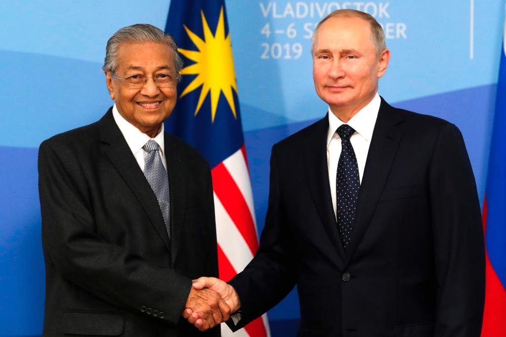 Russian President Vladimir Putin shakes hands with Prime Minister Tun Dr Mahathir Mohamad during their meeting at the Eastern Economic Forum in Vladivostok on September 5, 2019. - AFP