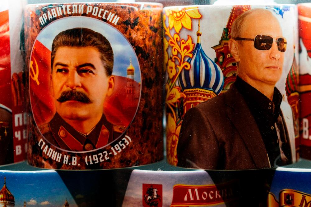 Mugs decorated with images of Russian President Vladimir Putin and Soviet leader Joseph Stalin are seen on sale among other items at a gift shop in Moscow on March 11, 2020. - AFP