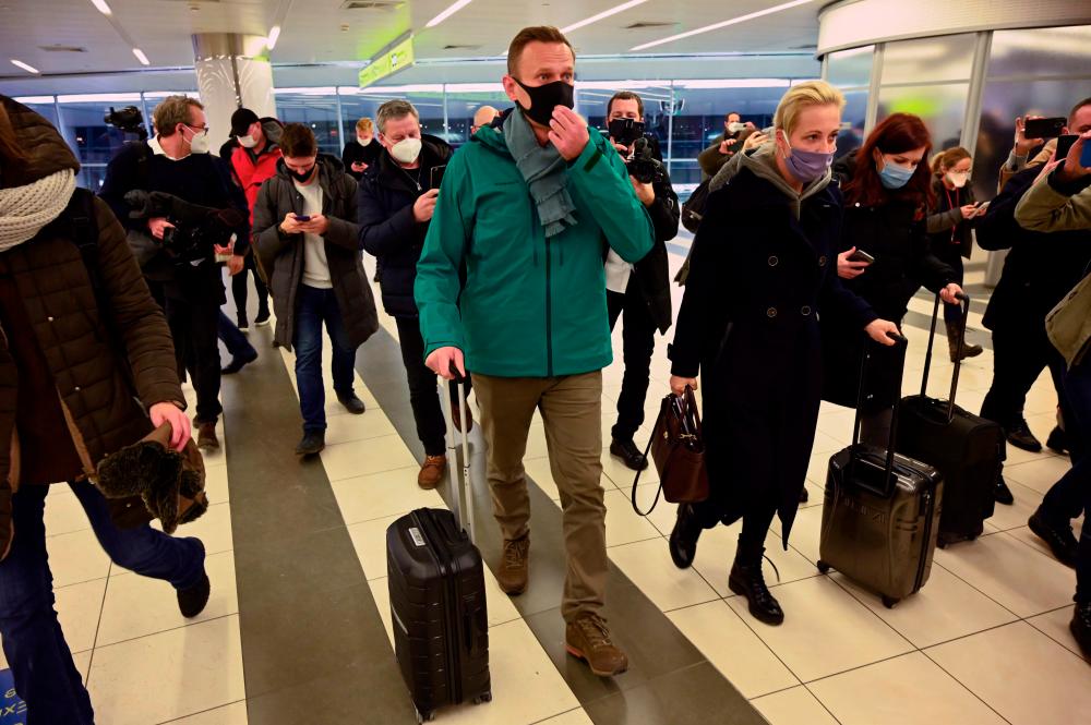 Russian opposition leader Alexei Navalny and his wife Yulia walk towards the passport control point at Moscow’s Sheremetyevo airport upon the arrival from Berlin on January 17, 2021. Russian police detained Kremlin critic Alexei Navalny at a Moscow airport shortly after he landed on a flight from Berlin, an AFP journalist at the scene said. / AFP / Kirill KUDRYAVTSEV