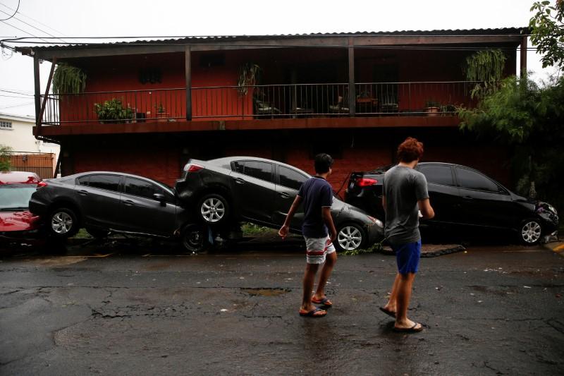 A woman walk in front of damaged cars during floods caused by Tropical Storm Amanda, in San Salvador, El Salvador May 31, 2020. -Reuters