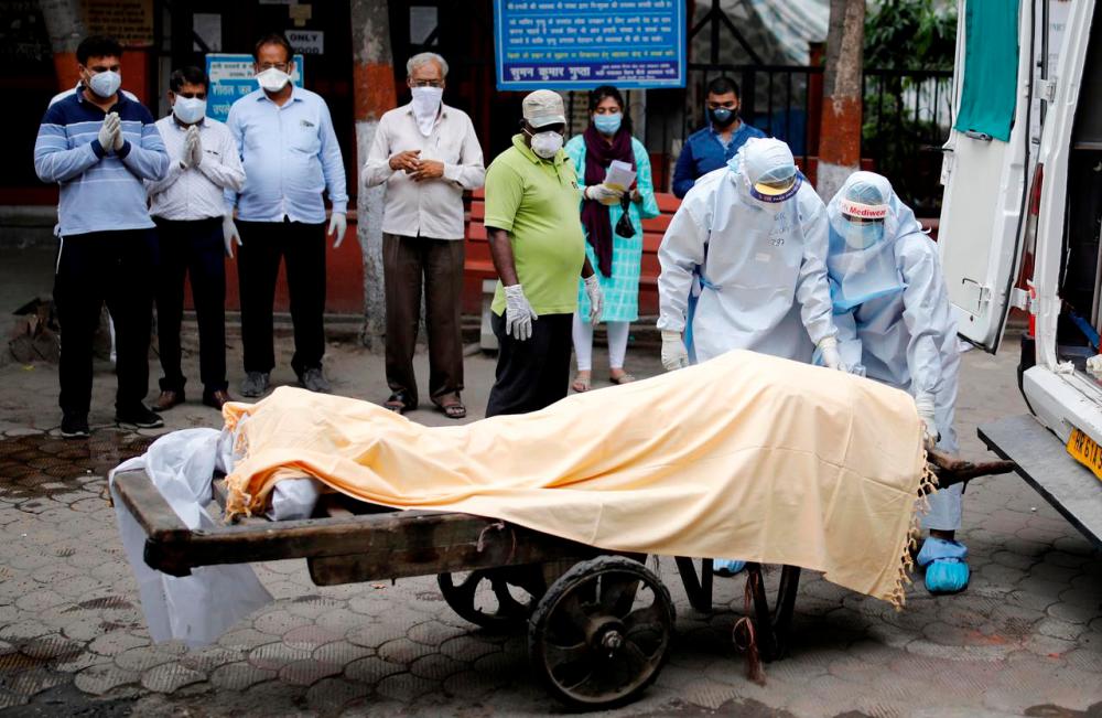 Health workers cover the body of a man who died due to the coronavirus disease (Covid-19), as relatives pay their respects, at a crematorium in New Delhi, India, June 4, 2020. -Reuters