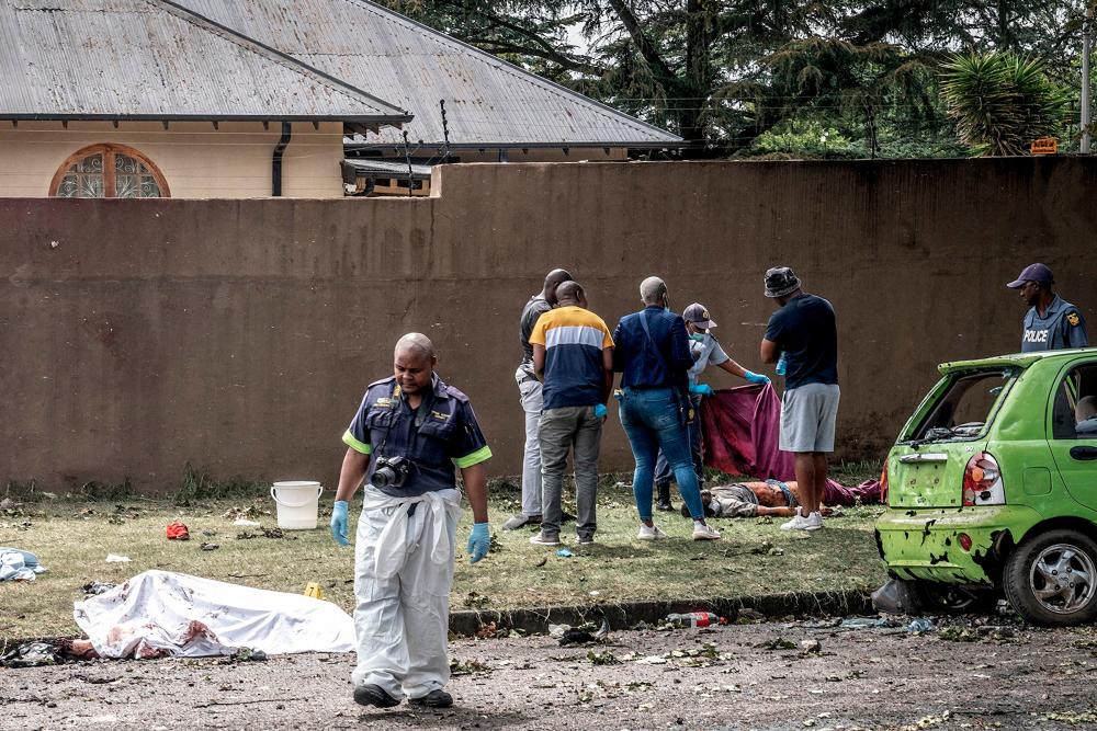 South African Police Service (SAPS) officers and forensic experts stand beside bodies in Boksburg, a city east of Johannesburg, on December 24, 2022, after nine people died and 40 others were injured when a fuel tanker exploded. AFPPIX