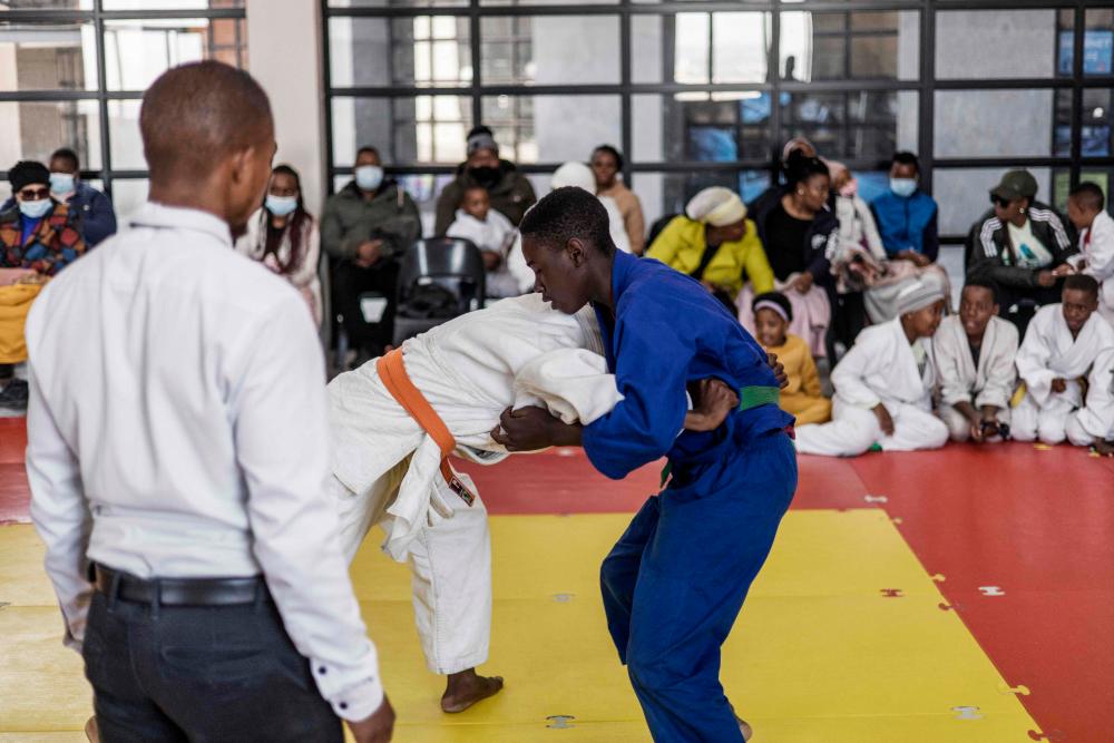 Zimbabwean green belt judoka Denzel Shumba, 17 (R), competes with South African orange belt judoka Lesego Rikhoto, 15 (L) in Johannesburg, on June 18, 2022 at the Dojo for Peace in the densely migrant populated district of Berea during a demonstration organised to celebrate International World Refugee Day. AFPPIX