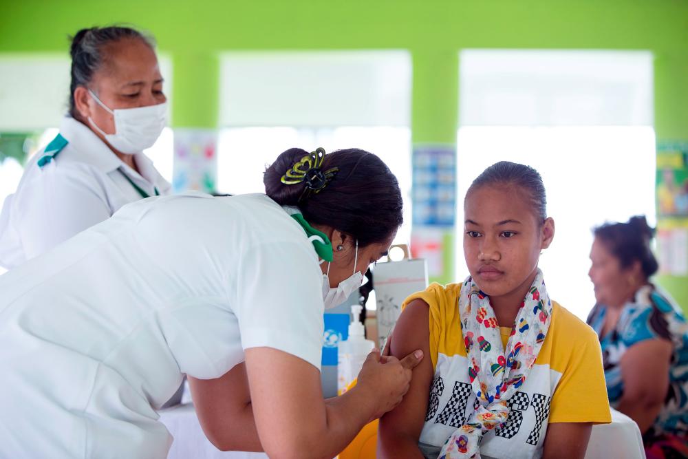 This handout picture taken on Dec 2, and released from Unicef Samoa on Dec 4 shows a girl receiving a vaccine during a nationwide campaign against measles in the Samoan town of Le'auva'a. — AFP