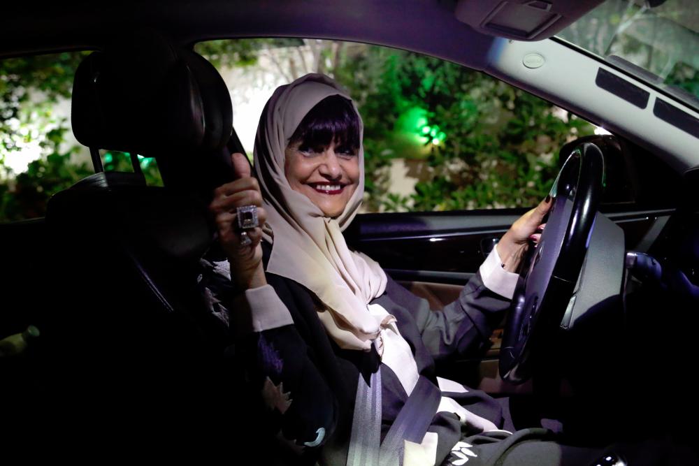 Munirah al-Sinani, a 72-year-old Saudi woman, gestures a thumb up before driving her car in the eastern Saudi city of Dhahran on June 11, 2019. — AFP
