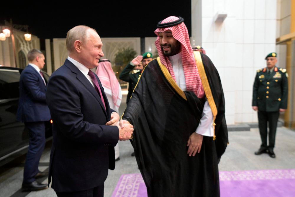 Pool photograph distributed by Russian state agency Sputnik shows Putin shaking hands with Prince Mohammed bin Salman ahead of their talks in Riyadh on Wednesday. – AFP